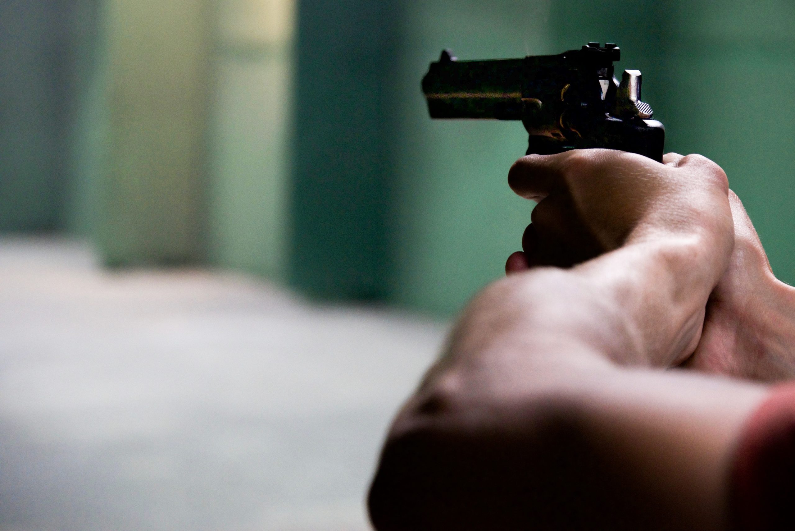 A man holding and pointing a handgun.